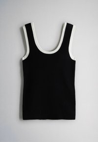 Débardeur noir sans manches avec une large bordure blanche autour du col et des emmanchures sur un fond gris clair.
