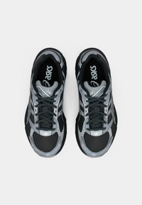 Juodi ir pilki sportiniai batai su tinkliniu ir sintetiniu viršumi, raišteliais, paminkštintu kraštu ir storu padu. Pasižymi ryškiu prekių ženklu.