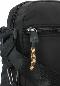 Black fabric shoulder bag with a zipper, featuring a textured strap and a patterned zipper pull in black and orange tones.