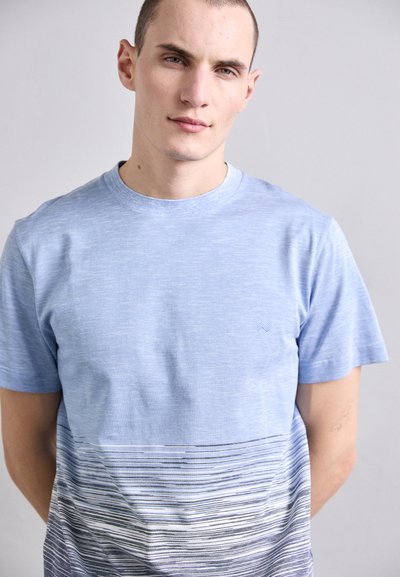 Lys blå crew-neck t-skjorte med et gradientdesign med horisontale striper som går fra lys til mørk blå. Korte ermer.