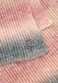 Prenda de punto en colores degradados desde rosa hasta gris, con una placa de logotipo plateada. La textura es suave con canalé visible.