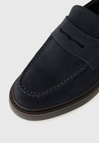 Mocassin navy en daim à enfiler, avec une tige texturée, des détails cousus et une semelle en caoutchouc durable avec un léger rebord.