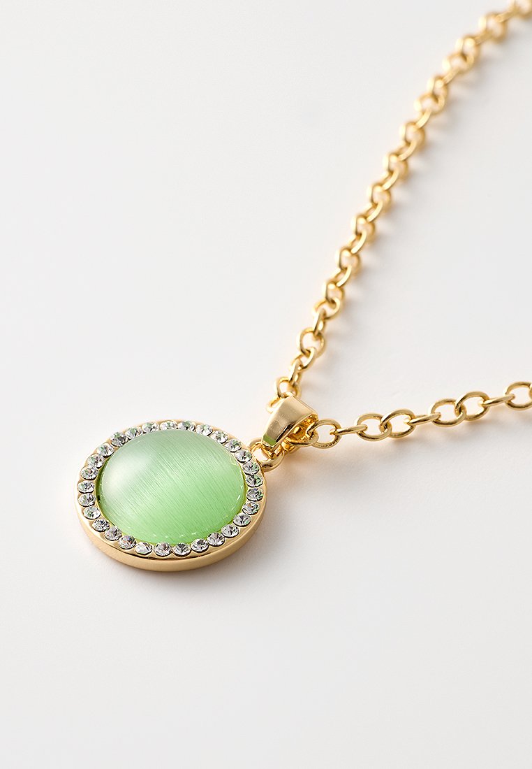 Collar de cadena de oro que presenta un colgante circular verde con una textura cepillada, rodeado por un anillo de pequeñas piedras de strass transparentes.