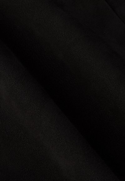 Schwarzer Wildlederstoff mit einer glatten Textur, die weiche, gedämpfte Wellen und einen subtilen Glanz auf der Oberfläche zeigt.