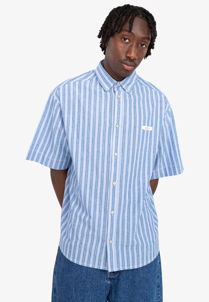 Camicia a maniche corte con bottoni di colore azzurro chiaro, con righe verticali bianche e rosa. Presenta un colletto e un'etichetta sul petto a sinistra.