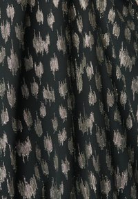 Tissu noir avec des taches abstraites métalliques argentées irrégulières en motifs verticaux et plis doux.