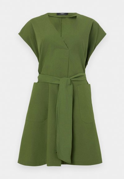 Robe vert olive à manches courtes, décolleté en V, deux poches avant et une ceinture nouée à la taille. Fabriquée en tissu léger.