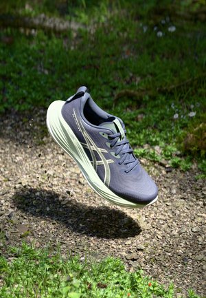 Botte de course avec un dessus gris foncé et une semelle vert clair, présentant un tissu texturé, un design à lacets, et une visibilité de la marque sur le côté.