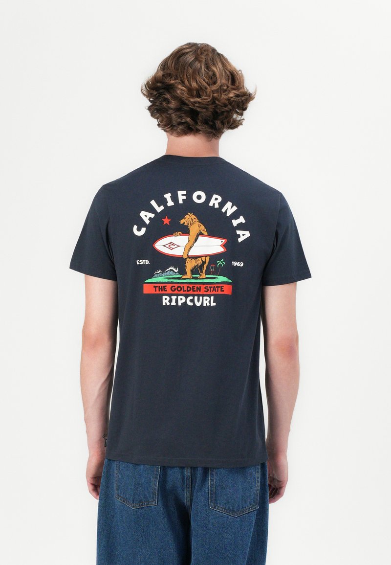 Marineblå bomull T-skjorte med et grafisk motiv av en bjørn som holder et surfebrett, med "CALIFORNIA," stjerner og "RIPCURL" i fet skrift.