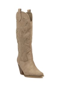 Bota vaquera de ante beige con puntera puntiaguda, caña alta, patrón intrincado de recortes y strass decorativos. Diseño con tacón cuadrado.