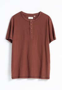 Camiseta de manga corta color óxido, hecha de una tela suave, con un cuello redondo, tapeta de botones y un dobladillo recto.