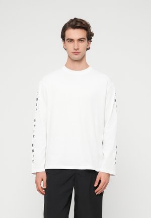 Weißes langärmeliges T-Shirt aus Baumwolle mit schwarzem "DRIP"-Schriftzug entlang beider Ärmel, Rundhalsausschnitt und lockerer Passform.