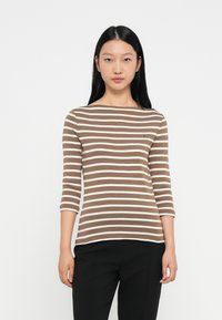 Μπλε και λευκή ριγέ μπλούζα με μακριά μανίκια και στρογγυλή λαιμόκοψη, φτιαγμένη από μαλακό ύφασμα. Διαθέτει ένα μικρό λογότυπο στο στήθος.