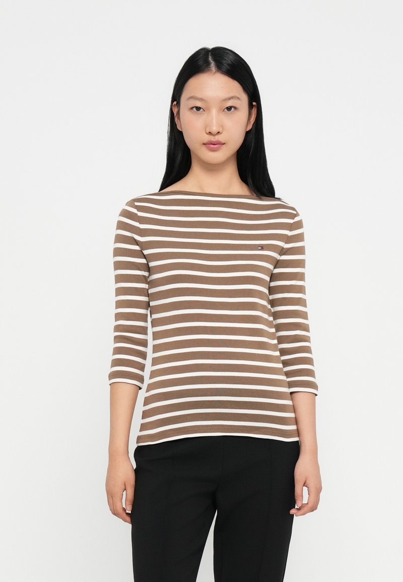 Μπλε και λευκή ριγέ μπλούζα με μακριά μανίκια και στρογγυλή λαιμόκοψη, φτιαγμένη από μαλακό ύφασμα. Διαθέτει ένα μικρό λογότυπο στο στήθος.