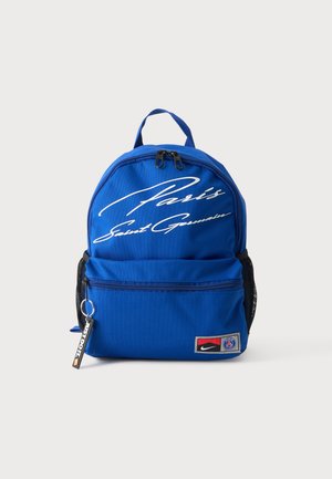 Sac à dos bleu avec le texte "Paris Saint Germain", une poche zippée avant avec les logos Nike et PSG, et un porte-clés "Just Do It" sur un fond gris.