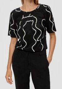 Černý top s bílými vlnkovými liniemi, s kulatým výstřihem a krátkými rukávy. Materiál vypadá hladce s jemným leskem.