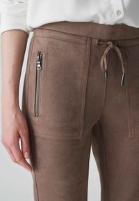 Braune Wildleder-Jogginghosen mit einer Reißverschlusstasche vorne, verstellbarem Kordelzug in der Taille und glatter, weicher Textur.