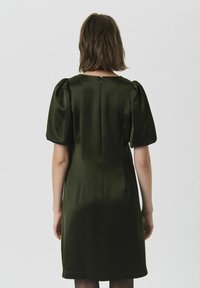 Rochie de satin verde închis, cu mâneci bufante, croială până la genunchi și un discret fermoar la spate. Textură netedă și siluetă ajustată.