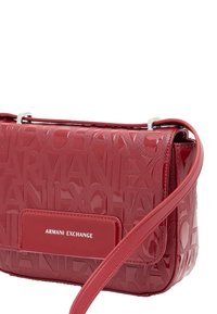 Borsa a tracolla rossa lucida con motivo testuale in rilievo "Armani Exchange" e una placca rettangolare con logo sul risvolto anteriore con una tracolla attaccata.