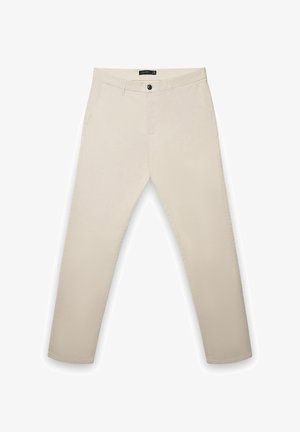Pantalon en coton beige à coupe droite, doté d'une fermeture à boutons, de poches latérales et de détails de couture subtils le long des coutures.