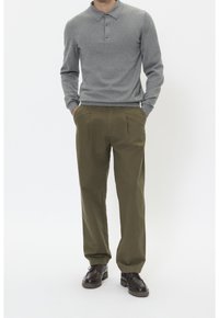 Grå långärmad polo med tre knappar, parat med olivgröna veckade byxor och mörkbruna snörskor.