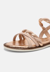 Sandale à lanières avec tige en cuir tressé couleur blush, accents métalliques, bout rond, semelle plate et semelle intérieure texturée.