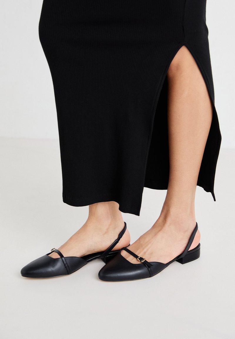 Ballerines noires en cuir avec un bout pointu, des fines sangles et un petit accent de boucle. Fini texturé avec un petit talon carré.