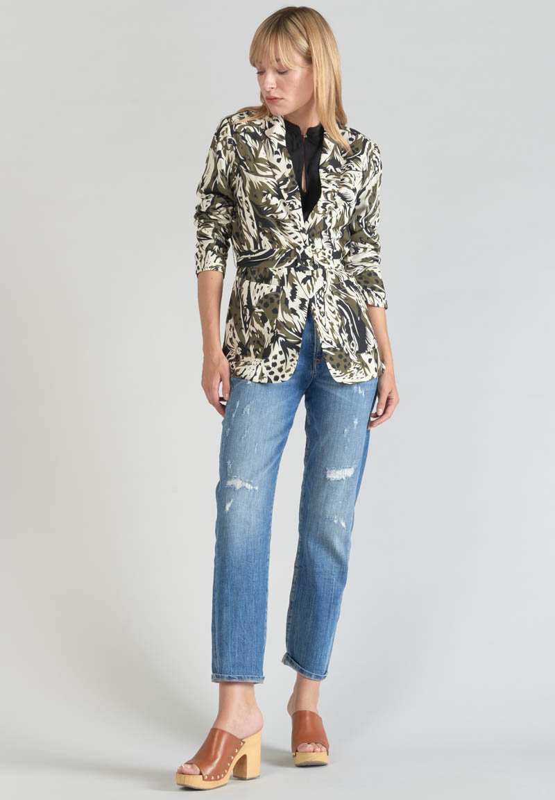 Floral-patterned blazer in green and beige tones, paired with distressed blue jeans and brown slide clogs with wooden soles.
