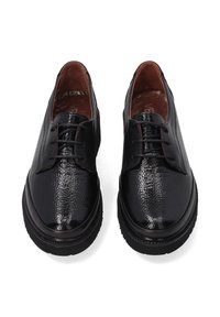 Schwarze, strukturierte Leder Schnürschuhe mit dicken Sohlen und braunen Innenausstattungen, von vorne oben auf einem weißen Hintergrund gezeigt.