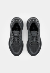 Černé běžecké boty s texturovaným síťovaným svrškem, zesílenou špičkou a plochými tkaničkami. Mají polstrovanou podrážku a prodyšný design.