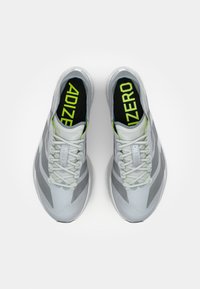 Svijetlosive atletske tenisice s modernim dizajnom, koje imaju teksturiranu površinu, limeta zelene detalje i logo "ADIZERO" na ulošcima.