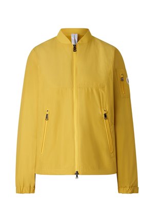 Jasnożółta lekka kurtka z przednim zamkiem błyskawicznym, zamykanymi na zamek kieszeniami bocznymi, małą kieszenią na zamek na lewym rękawie oraz elastycznymi mankietami.