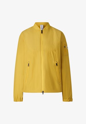 Jasnożółta lekka kurtka z przednim zamkiem błyskawicznym, zamykanymi na zamek kieszeniami bocznymi, małą kieszenią na zamek na lewym rękawie oraz elastycznymi mankietami.