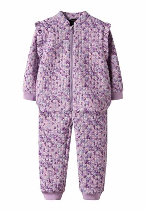 Quiltet lavendelfarget barneheldress med blomsterprint, frontglidelås, rysjedetaljer på skuldrene og mansjetter på ermer og ankler.