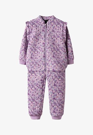 Combinaison matelassée pour enfants de couleur lavande avec motif floral, fermeture éclair à l'avant, détails à volants aux épaules, et manches ainsi que chevilles à revers.