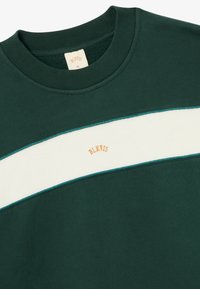 Σκούρο πράσινο φούτερ με κρέμα οριζόντια λωρίδα και αντίθετο τιρκουάζ επένδυση. Το "BLKVIS" είναι κεντημένο σε πορτοκαλί. Ριμπ μανίκι.