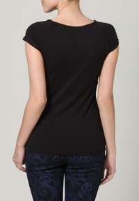 Svart t-shirt med kort ärm, rundad halsringning och figurnära silhuett. Tyget är slätt och verkar elastiskt, lämpligt f ör avslappnad klädsel.