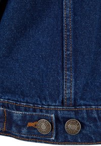 Tissu denim bleu foncé avec coutures orange et deux boutons métalliques étiquetés "Urban Classics" sur un ourlet de vêtement.
