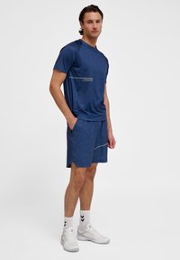 Marine sportoutfit met een geometrisch patroon op het shirt en bijpassende shorts. Het shirt heeft een logo aan de voorkant, met reflecterende accenten.