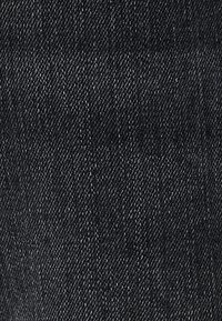 Tessuto di denim nero caratterizzato da una trama liscia con un classico motivo in twill, contraddistinto da sottili variazioni di tonalità e lucentezza.