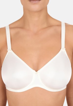 Frau trägt einen glatten, weißen Bügel-BH mit dünnen verstellbaren Trägern und kleinen Schleifen an den Trägern sowie in der vorderen Mitte.