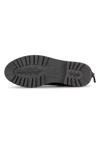 Semelle en caoutchouc noir avec un motif de semelle texturé, présentant de profondes rainures et un talon renforcé pour une adhérence et une durabilité accrues.
