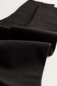 Tela negra con una textura suave, que muestra pliegues y una forma rectangular. Sin patrones visibles ni herrajes.