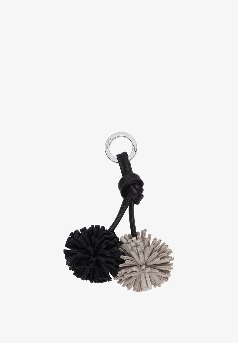 Porte-clés avec deux pompons en cuir, l'un noir et l'autre beige, attachés à un anneau métallique argenté avec une lanière en cuir noir nouée.