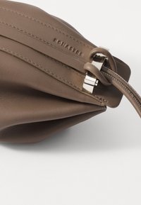Brown leather pouch with a textured finish, silver hardware, a secure zipper, and knot detail on the strap. Compact and soft structure.