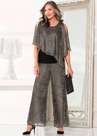 Top argento scintillante con spalline scoperte, indossato su una maglietta nera, abbinato a pantaloni argento a gamba larga. Tessuto texturizzato, design dalle spalle scoperte e clutch nera.
