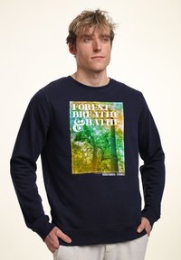 Felpa blu marina con grafica di un albero, che presenta il testo "FOREST BREATHE & BATH" in bianco e accenti colorati. Polsini e scollatura a costine.