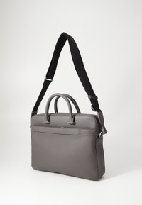 Grau Ledertasche mit zwei oberen Griffen, verstellbarem schwarzen Riemen, glatter Oberfläche und einer Vordertasche im minimalistischen Design.