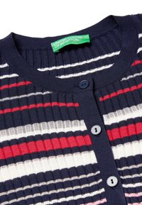 Námořnický svetr s vertikálním žebrováním, zdobený vícebarevnými horizontálními pruhy v červené, bílé a růžové barvě. Tři modré knoflíky vepředu.