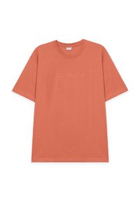 Camiseta naranja de algodón de manga corta con cuello redondo y texto en relieve "Disfruta el viaje" centrado en el pecho.